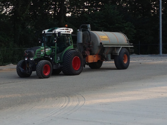 Tractor met watertank op de ondergrond van een sportveld