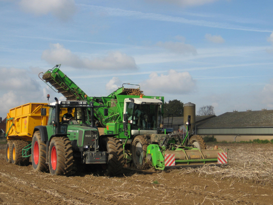 Aardappelrooien met tractor en rooimachine op een akker